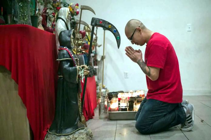 devoto ofrece oraciones a una estatua de La Santa Muerte